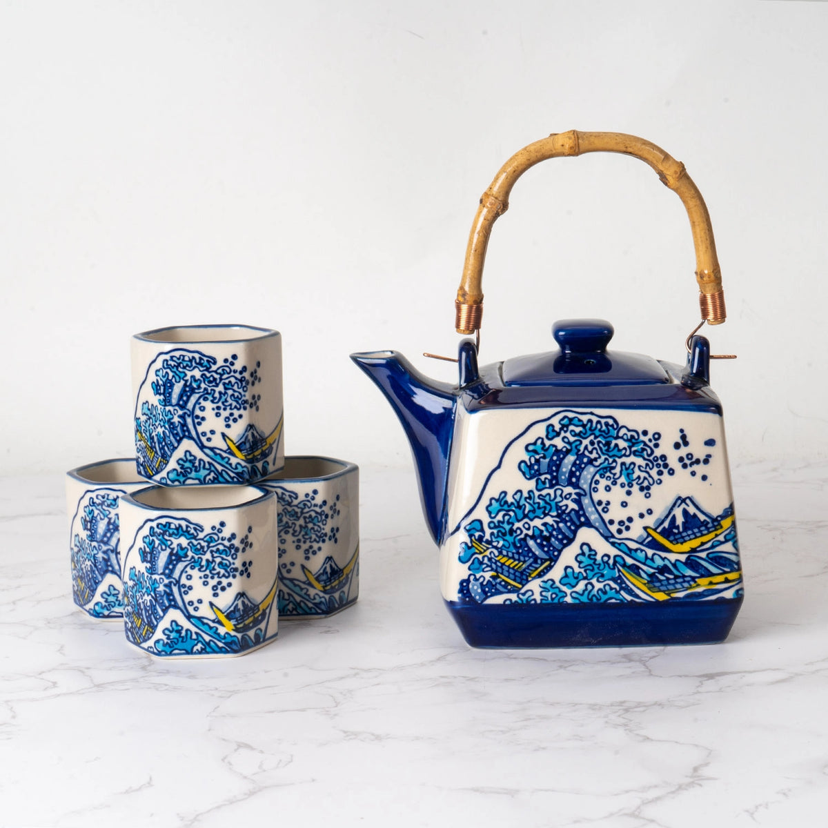 Ceramic teapot with bamboo handle and four cups featuring The Great Wave off Kanagawa ocean wave design in blue and yellow.