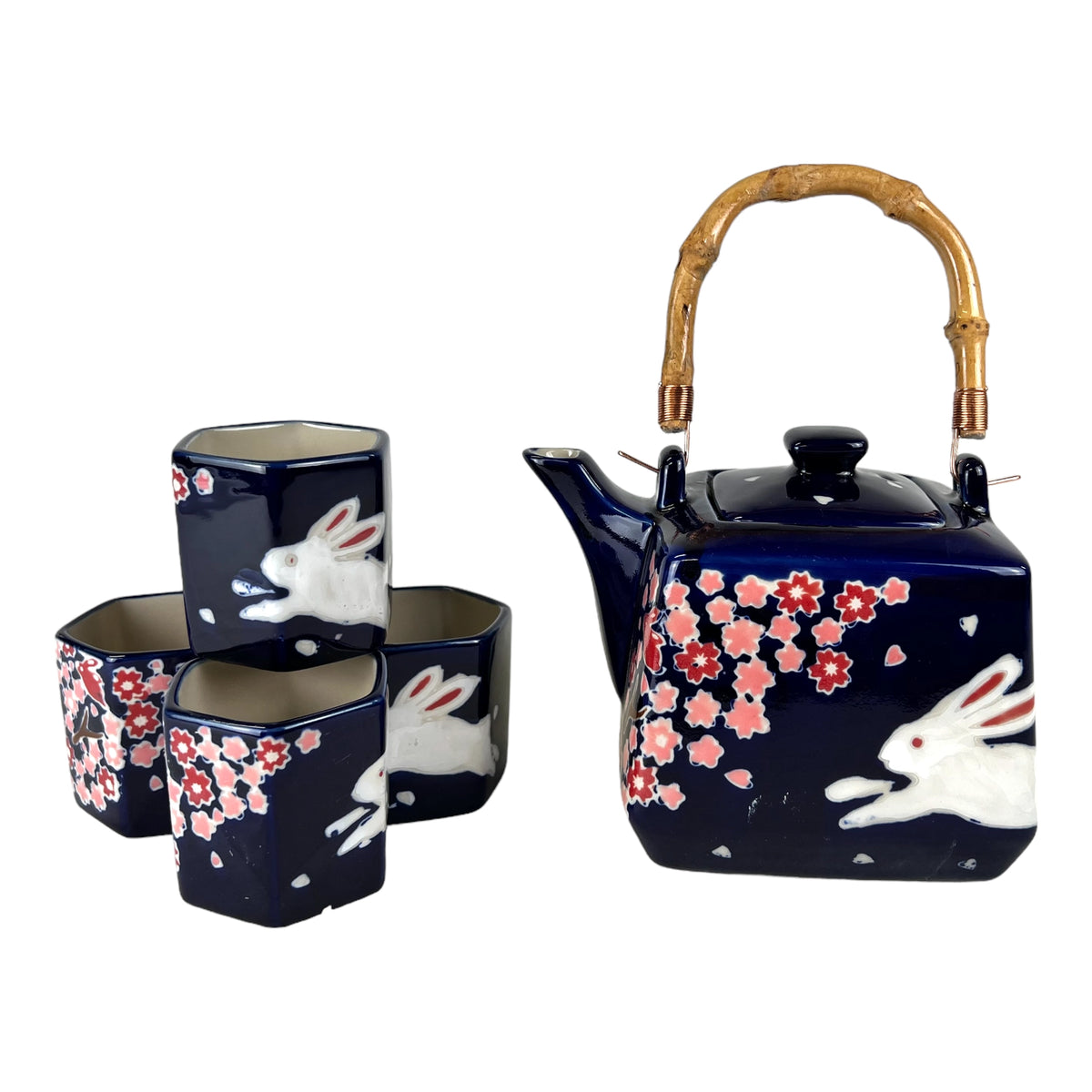 Navy-blue ceramic teapot with bamboo handle and four matching cups featuring pink cherry blossoms and white rabbits.