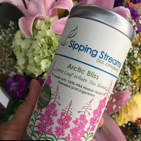 Tall tin of Sipping Steams Arctic Bliss loose leaf fireweed tea blend held in a hand.