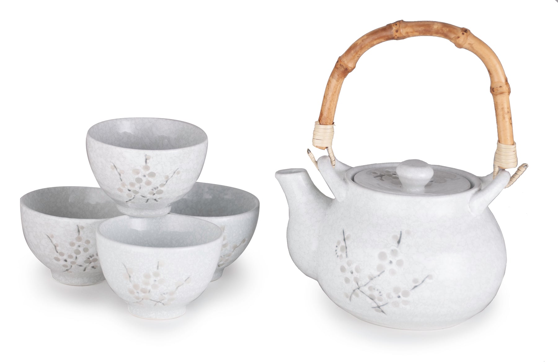 A cherry blossom tea set featuring a ceramic teapot with a natural bamboo handle and four matching cups.