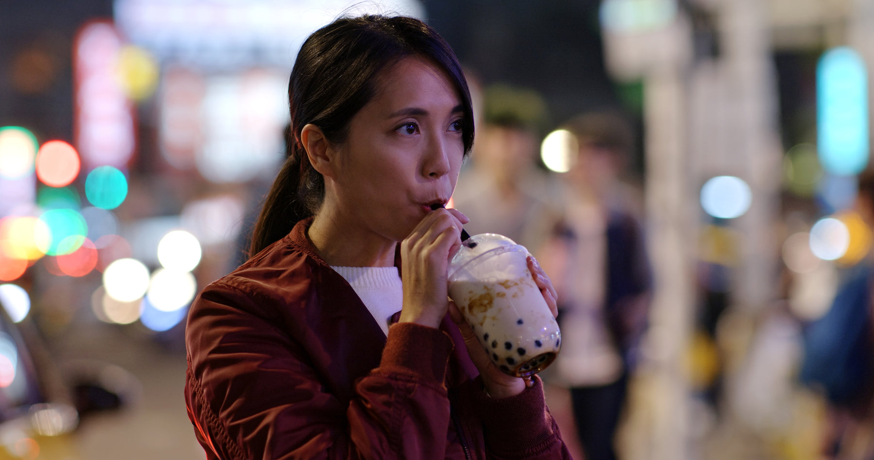 Woman drinking coconut bubble tea through a straw.