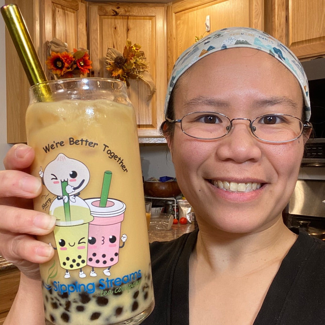 Jenny Tse holding a "We're Better Together" bubble tea glass with tea and straw.