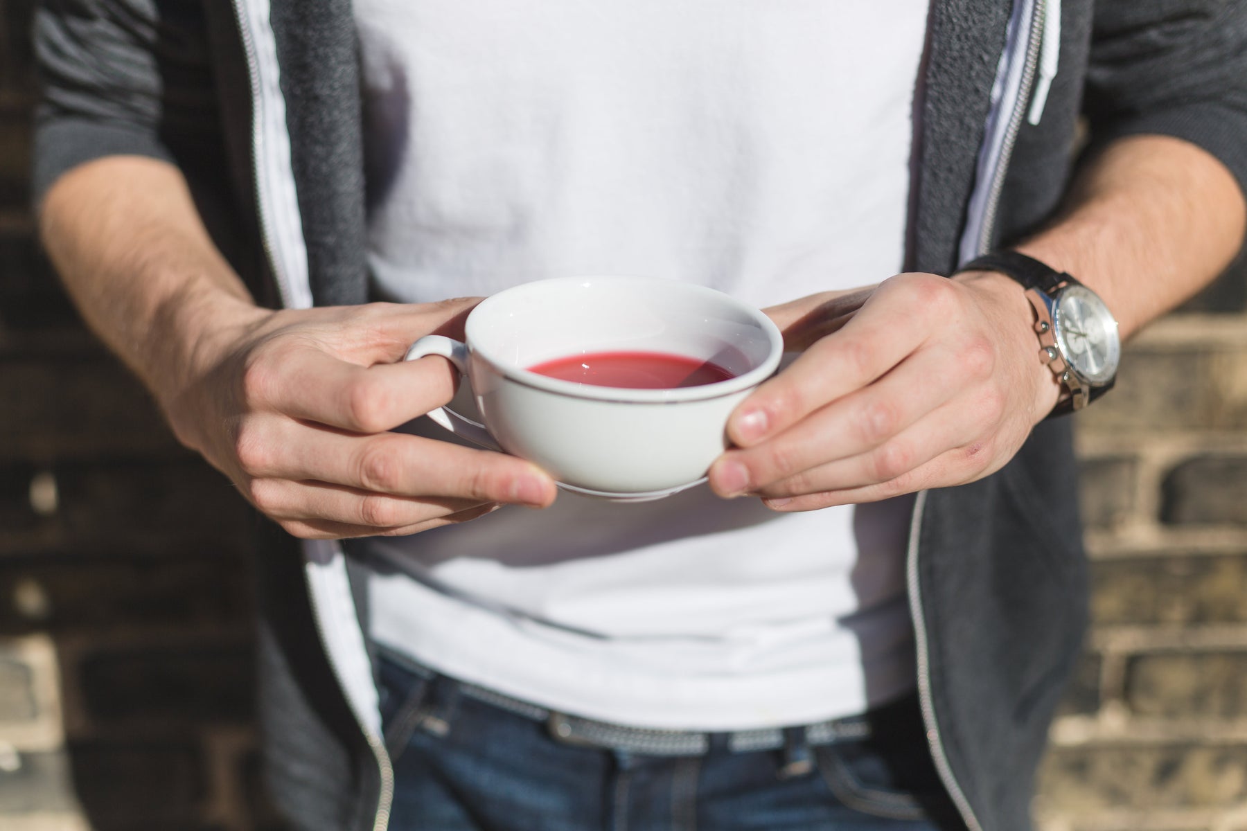 Cup of hibiscus tea in a man's hands.